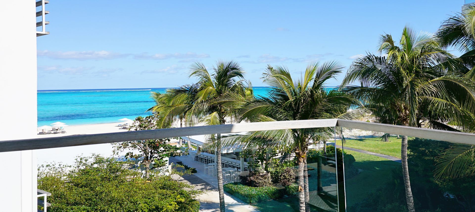 A balcony with a view of the ocean and palm trees