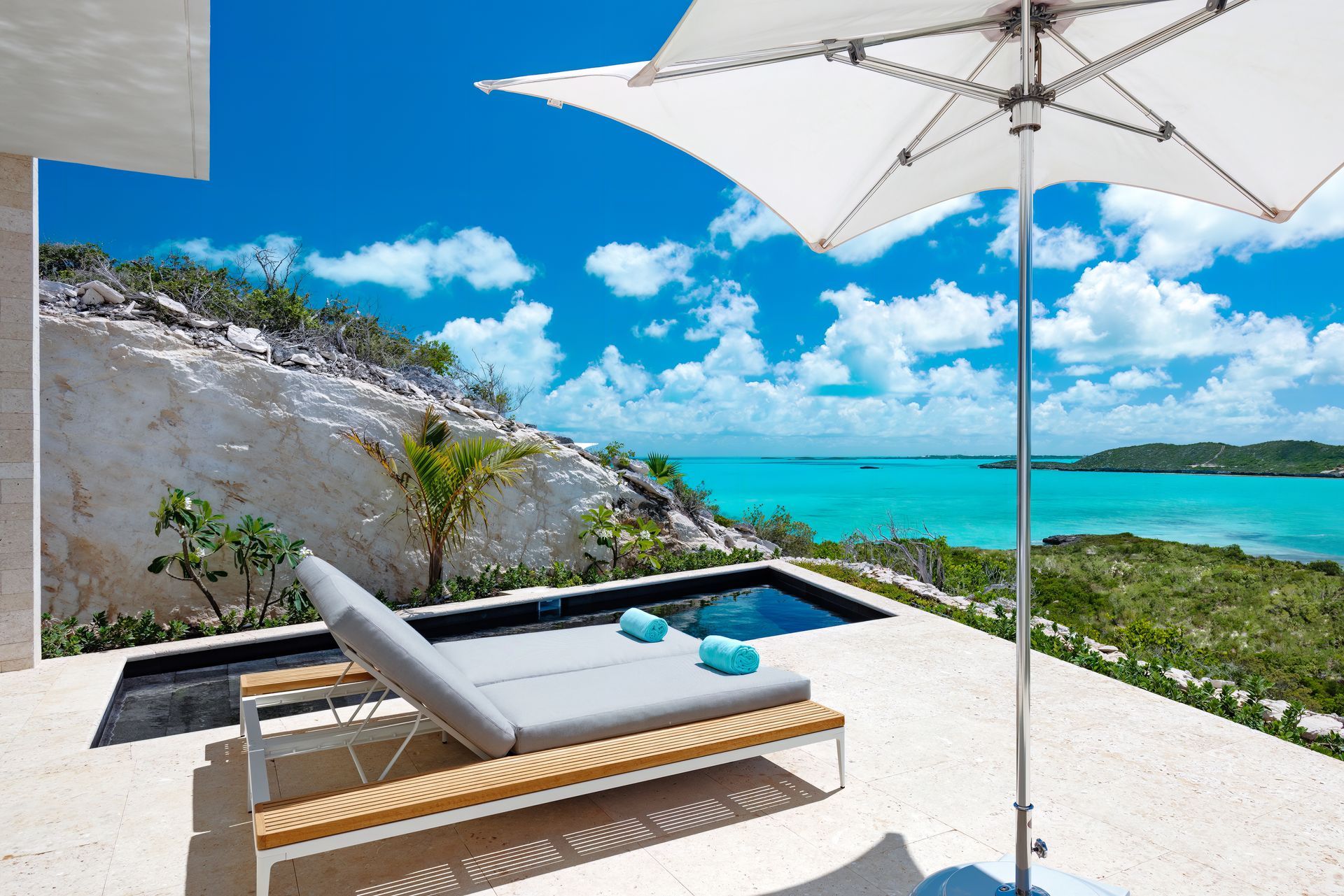 A swimming pool with two lounge chairs and an umbrella