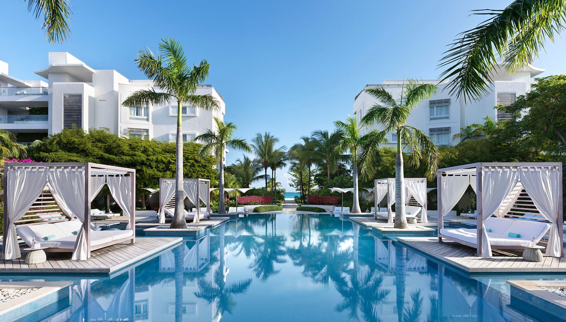 A large swimming pool surrounded by white buildings and palm trees