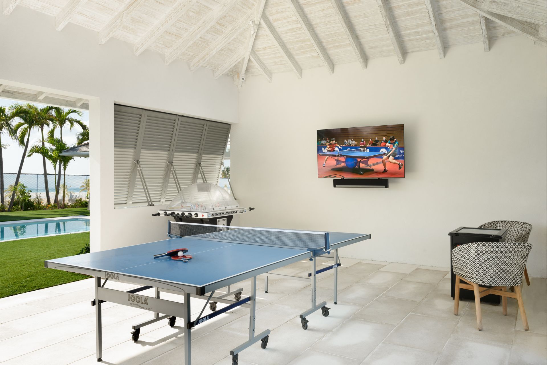 A ping pong table in a room with a television on the wall