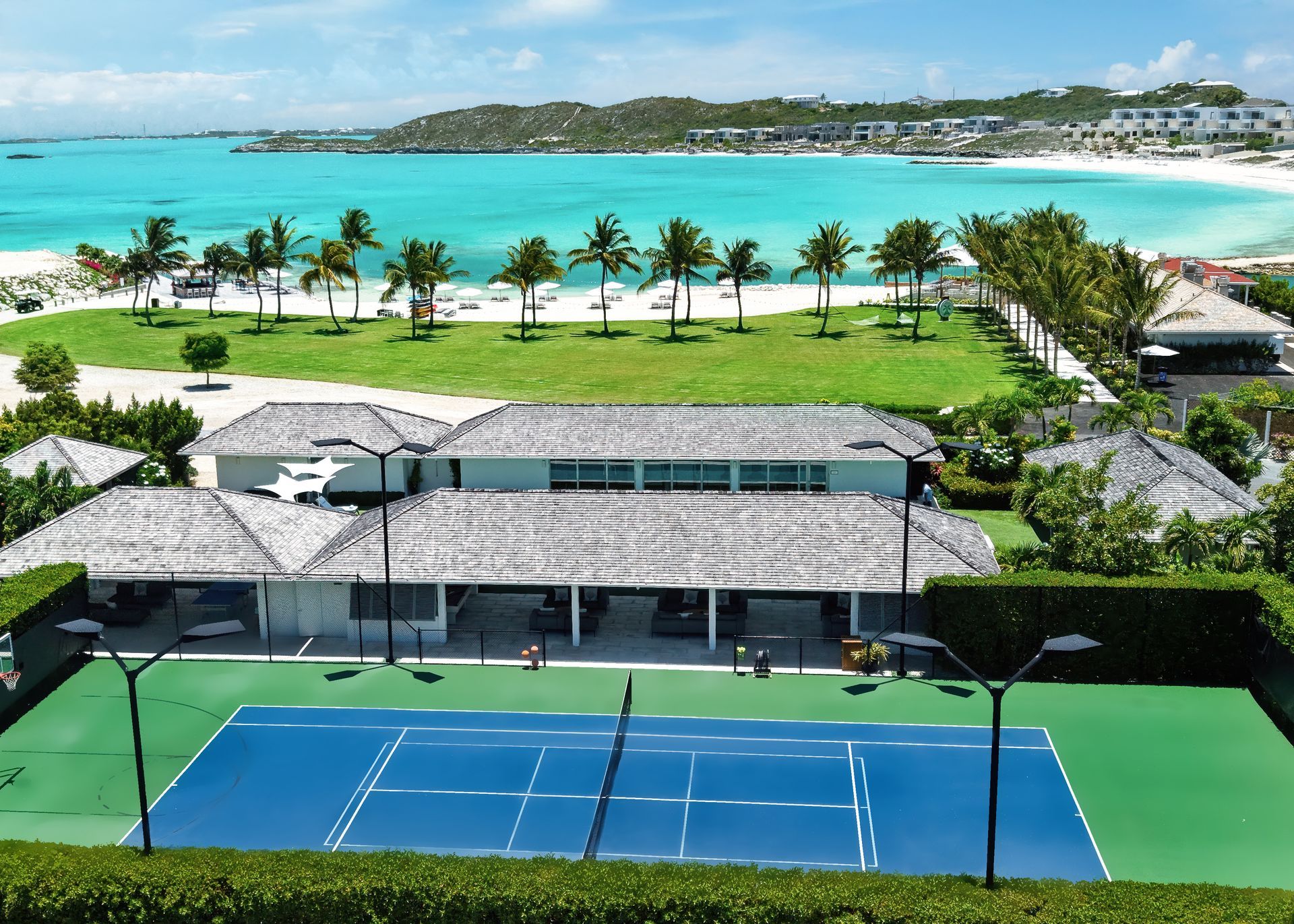 An aerial view of a tennis court with the ocean in the background