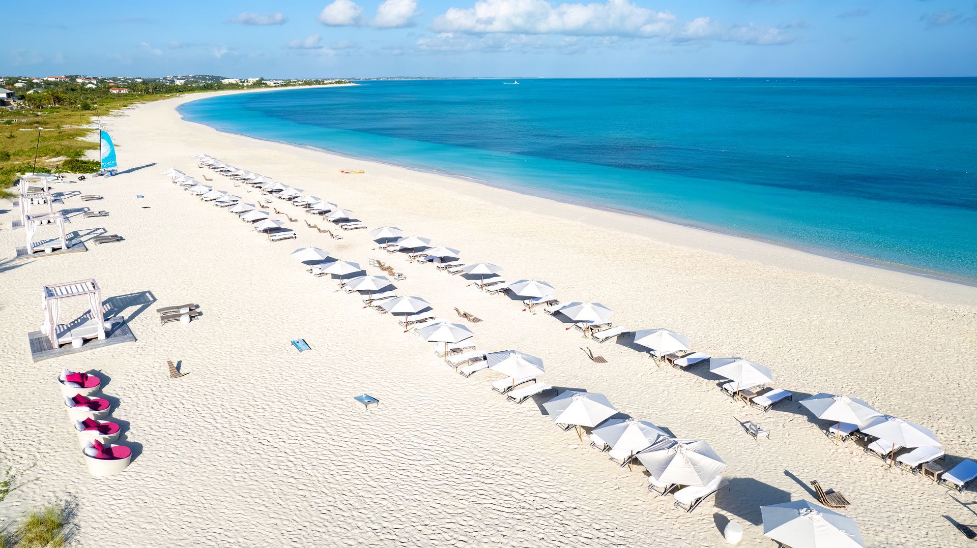 An aerial view of a beach with chairs and umbrellas