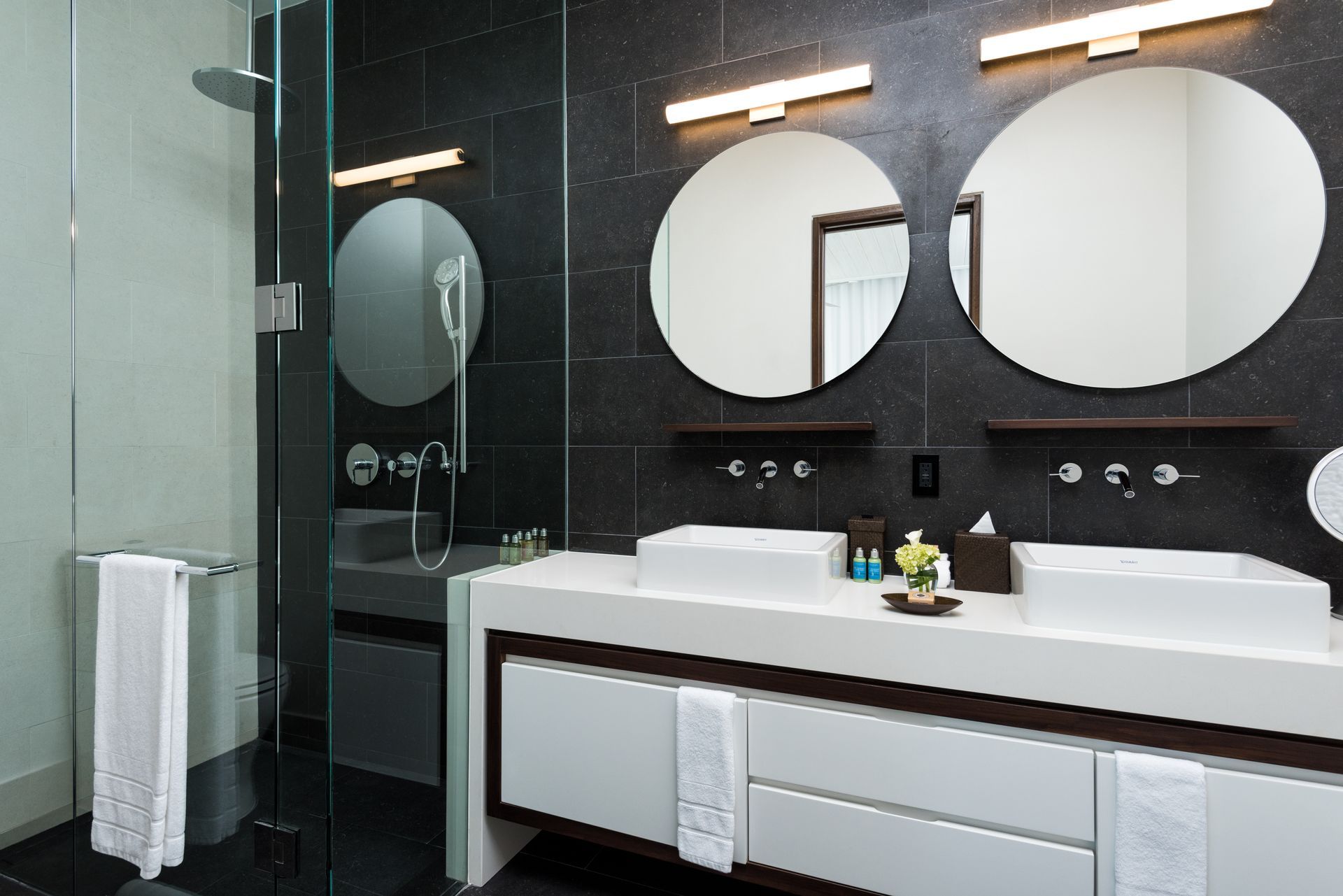 A bathroom with two sinks and two round mirrors