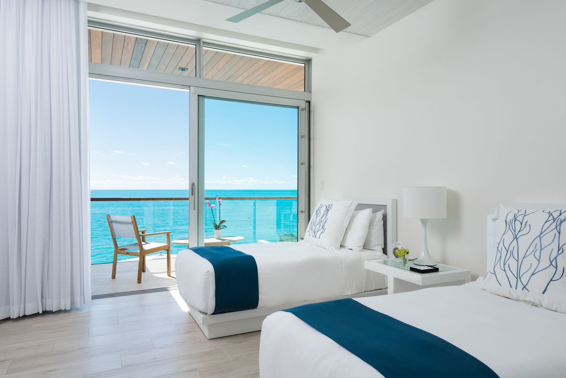 A hotel room with two beds and a balcony overlooking the ocean