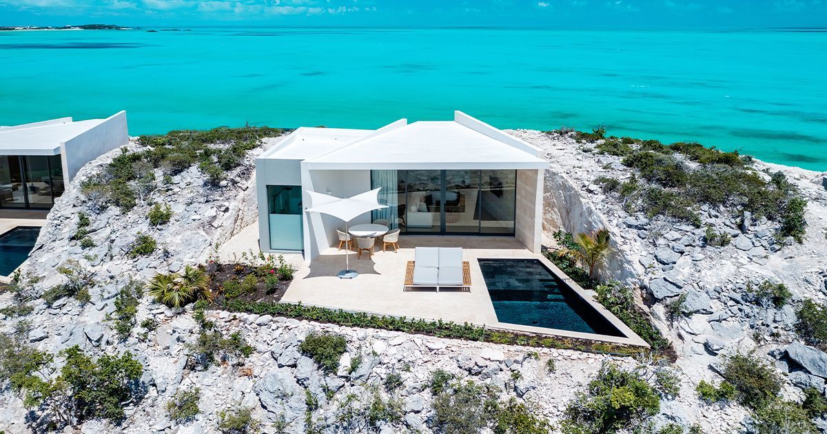 A white house sits on top of a sandy hill overlooking the ocean