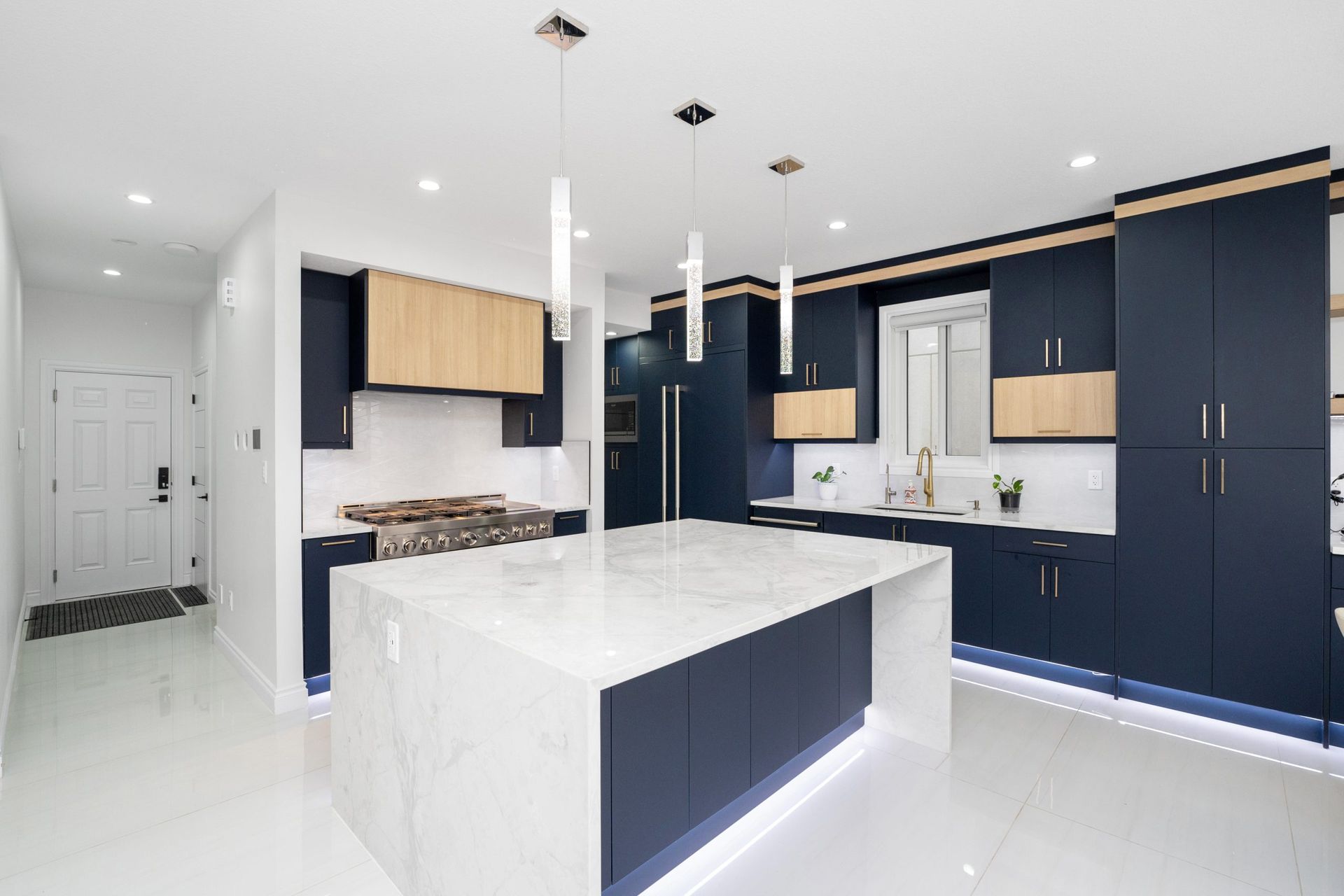 Modern kitchen with navy cabinets, white island, and bright marble-style finishes