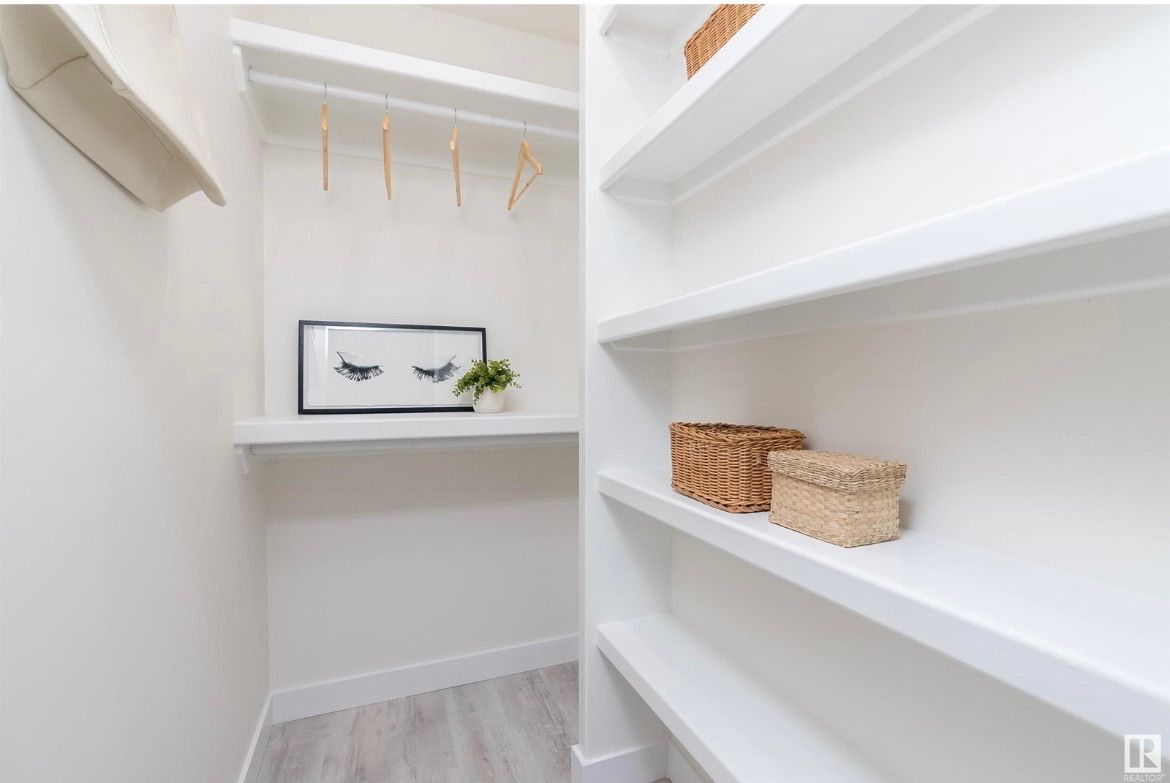 Bright walk-in closet with white shelves, hanging rods, and woven baskets.