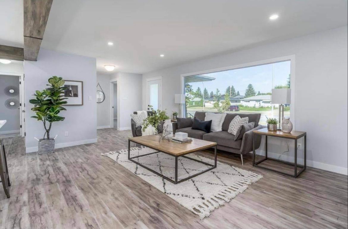 Modern living room with gray sofa, coffee table, large window, and wood-look floors