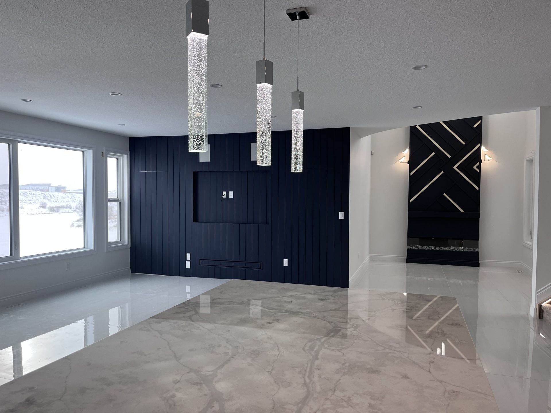 Modern empty living room with glossy marble floor, dark blue accent wall, pendant lights, and large windows