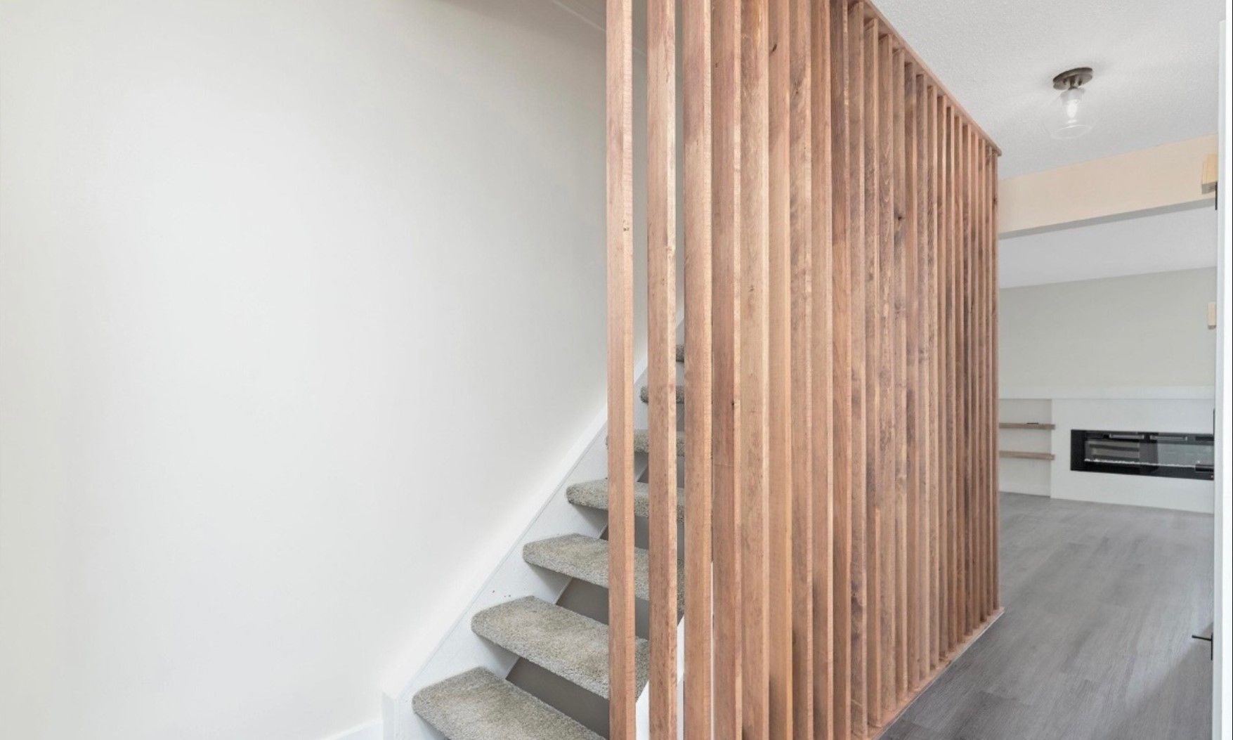 Indoor staircase with gray carpet and vertical wooden slat divider in a modern hallway