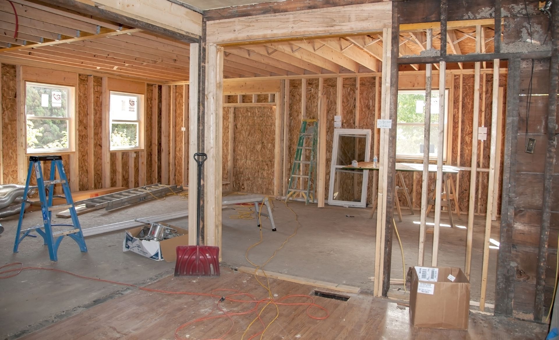 Interior renovation with exposed framing, ladders, and tools in an unfinished room