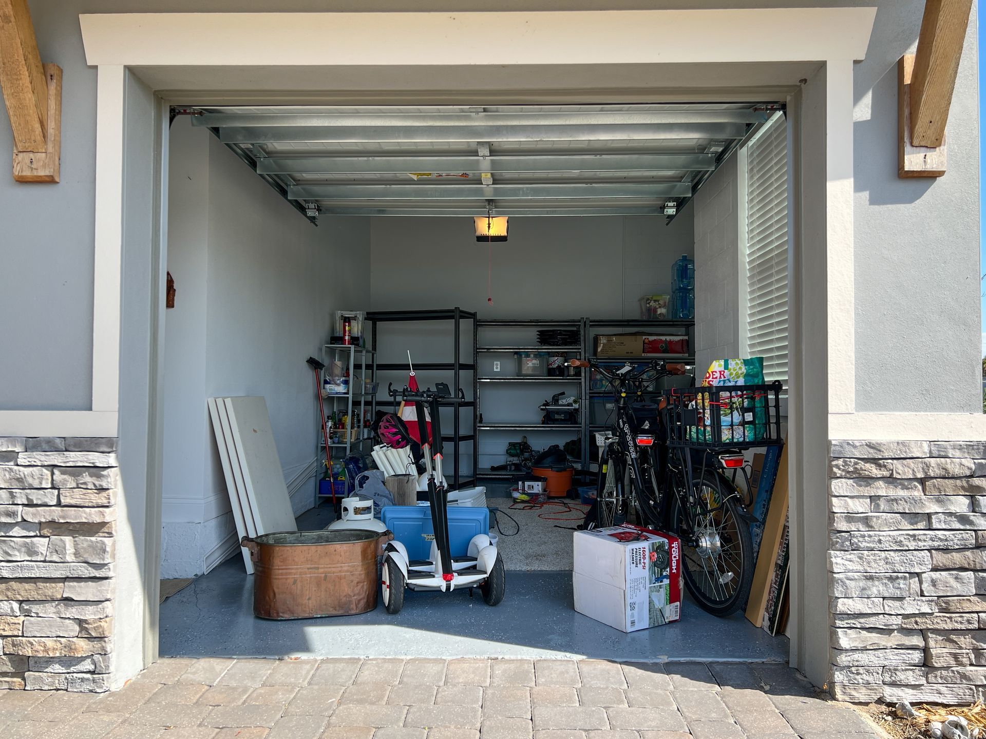 Open garage filled with storage shelves, tools, and household items.