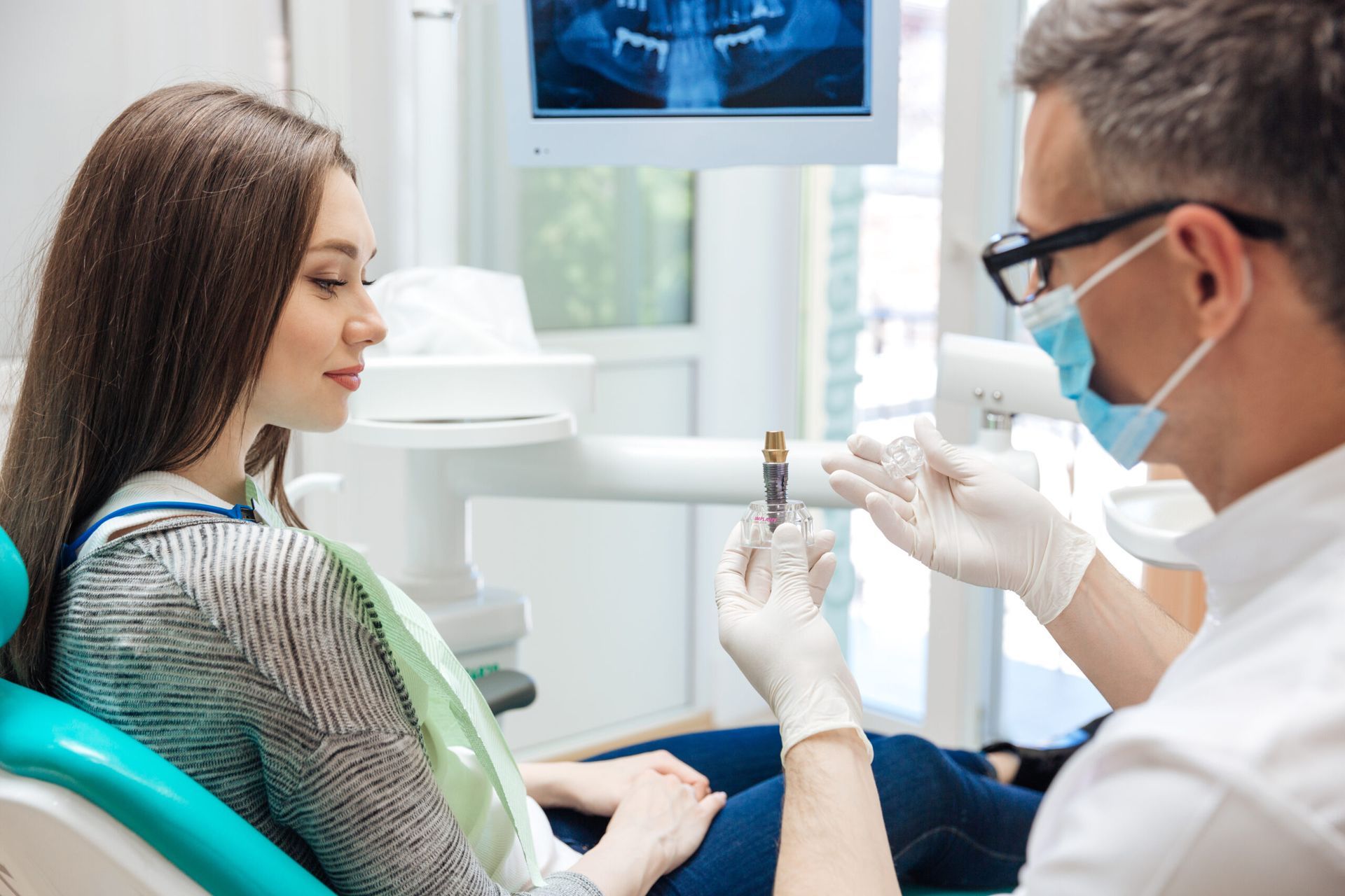 A woman is sitting in a dental chair talking to a dentist.