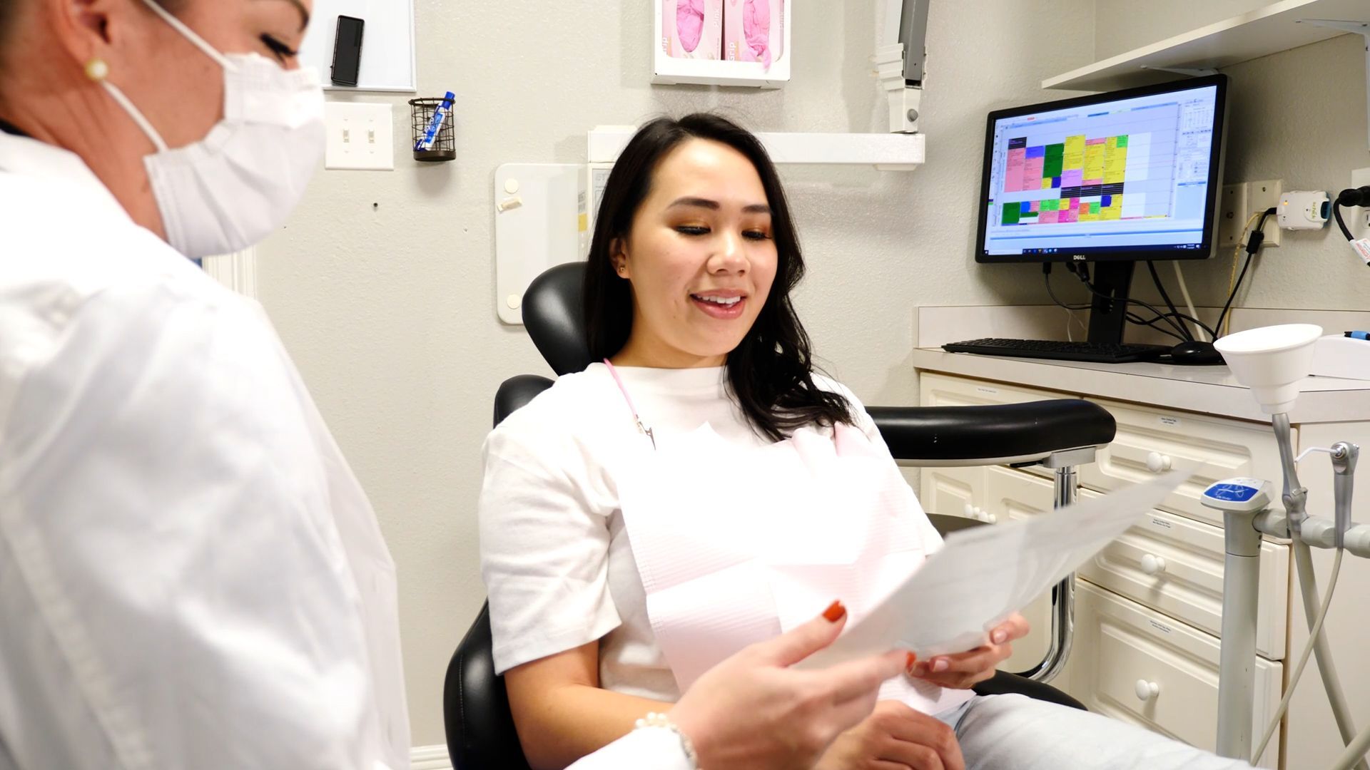 A woman is sitting in a dental chair talking to a dentist.