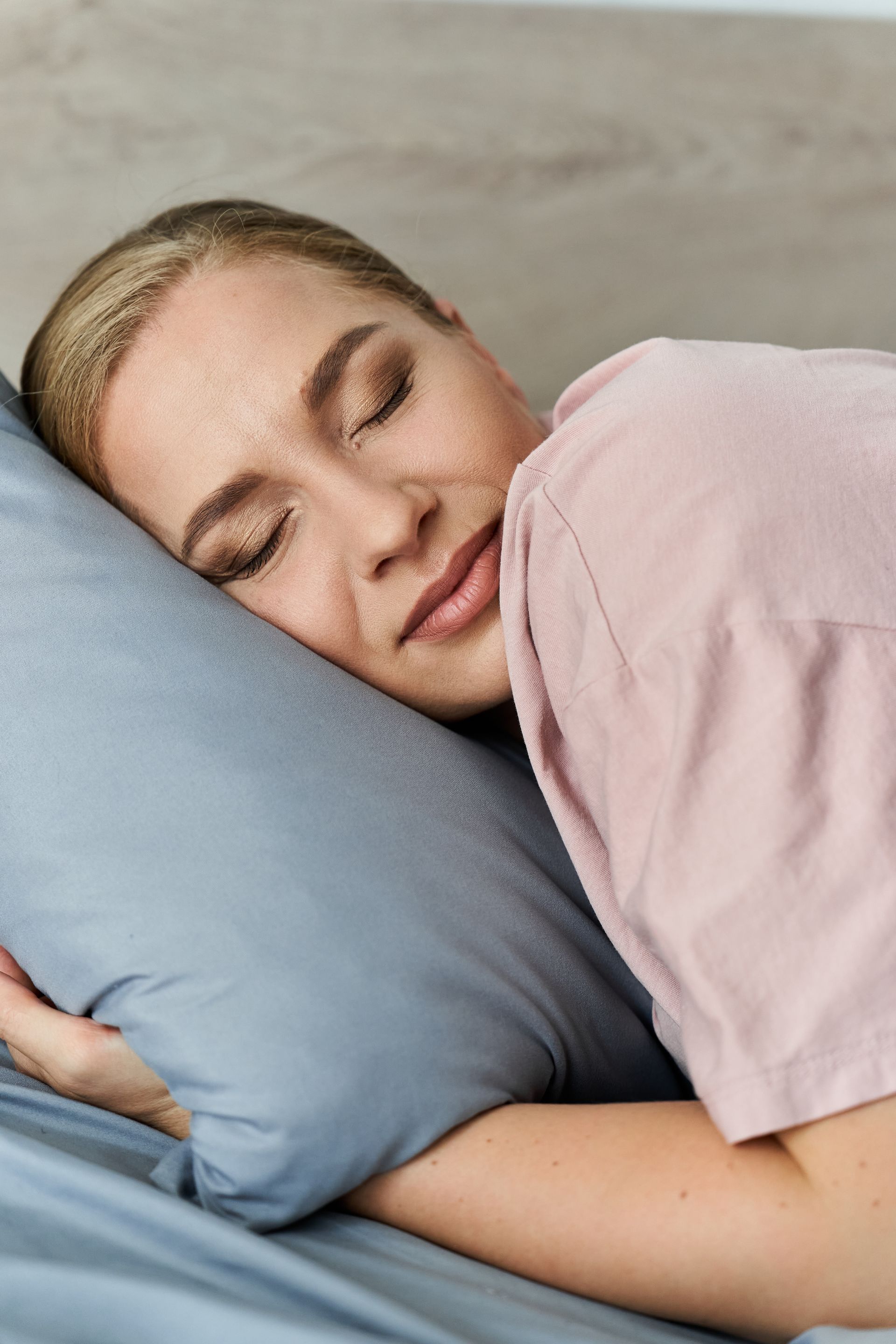 A woman is sleeping in a bed next to an alarm clock.