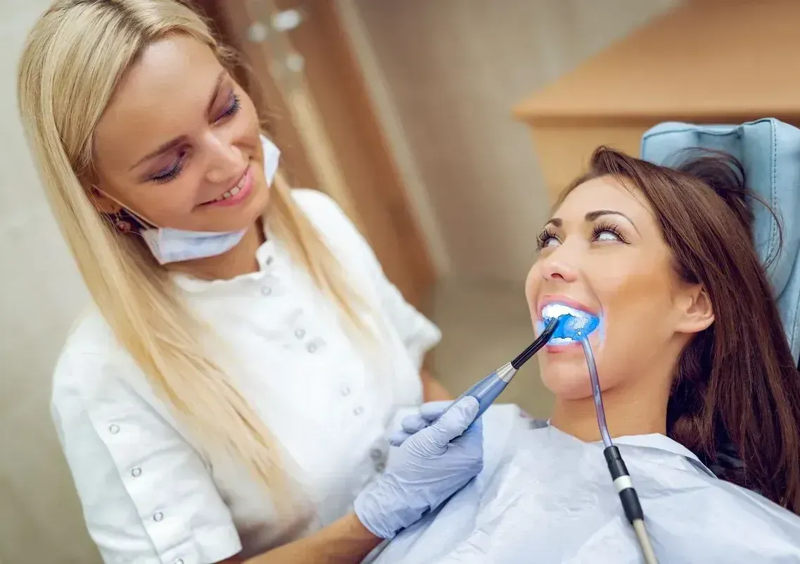 A woman is getting her teeth whitened by a dentist.