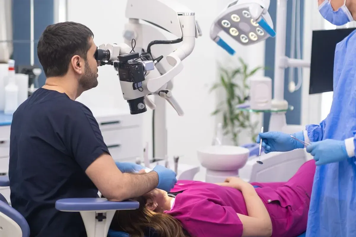 A dentist is examining a patient 's teeth under a microscope in a dental office.