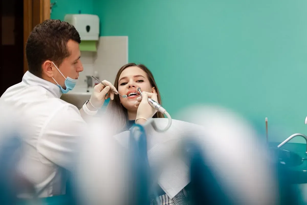 A dentist is examining a woman 's teeth in a dental office.