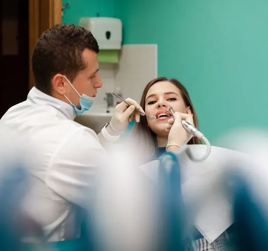 A dentist is examining a woman 's teeth in a dental office.