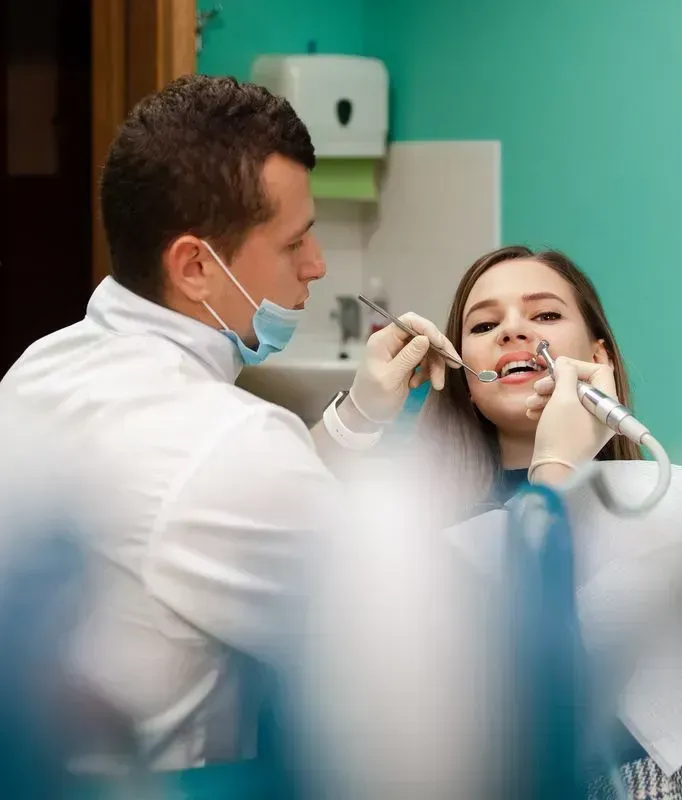 A dentist is examining a woman 's teeth in a dental office.