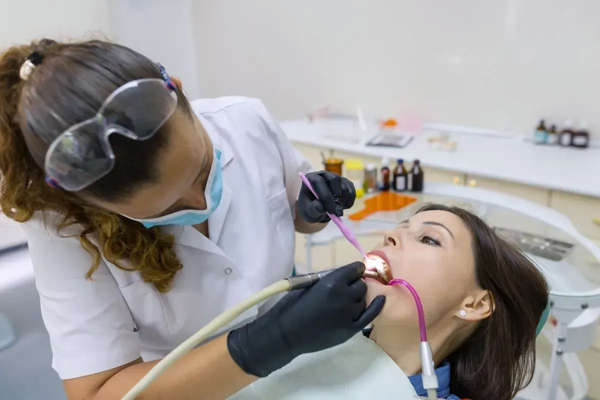 A woman is getting her teeth examined by a dentist in a dental office.