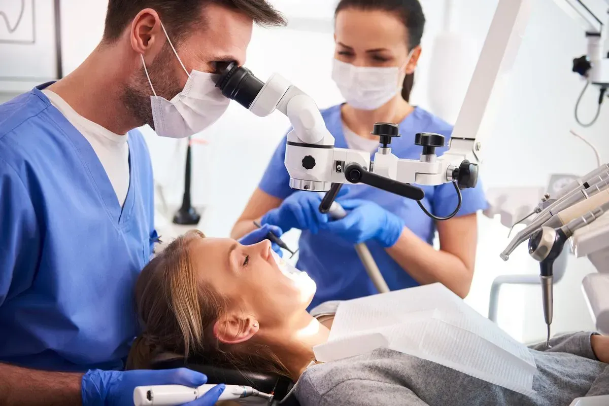 A dentist is examining a patient 's teeth under a microscope.