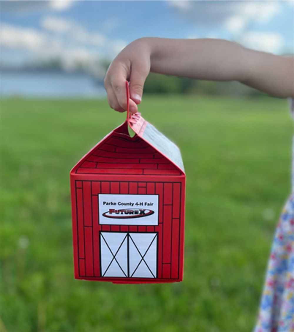 Child holding a red barn-shaped box, with 