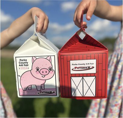 Two children holding barn and pig-shaped gift boxes at the Parke County 4-H Fair.