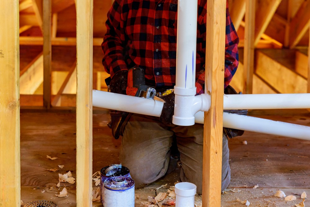 A man uses a wrench to adjust a water softener, a device designed to reduce mineral content in water for improved household water quality.