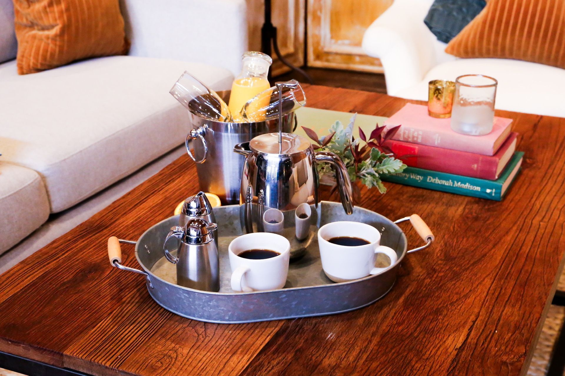 A tray with two cups of coffee and a bucket of ice sits on a wooden table.