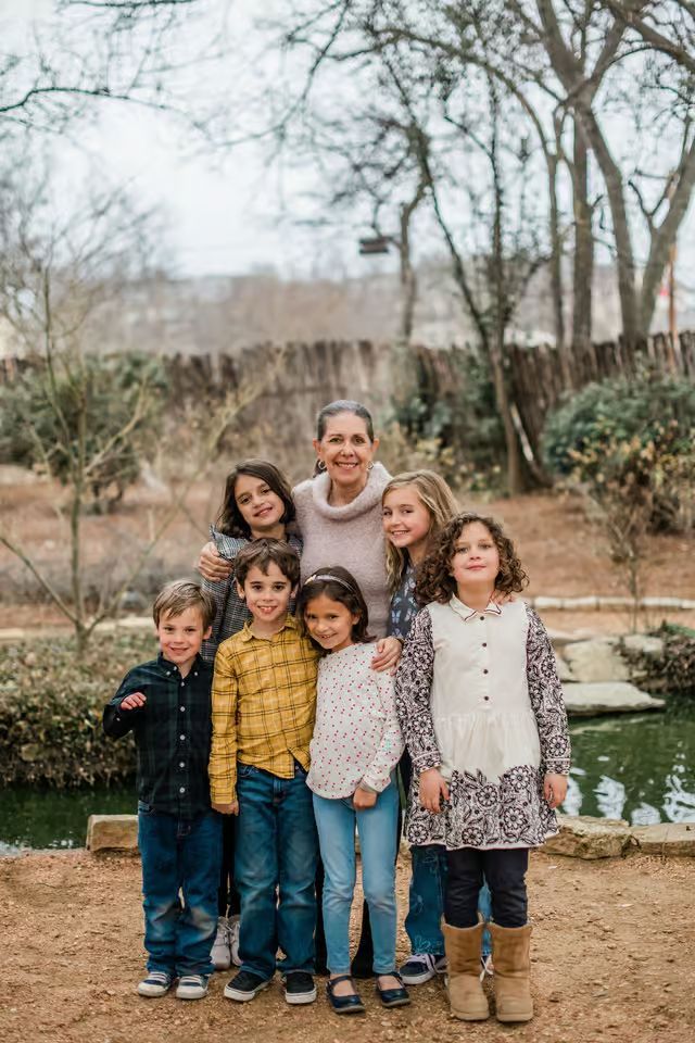 A family is posing for a picture in front of a pond.