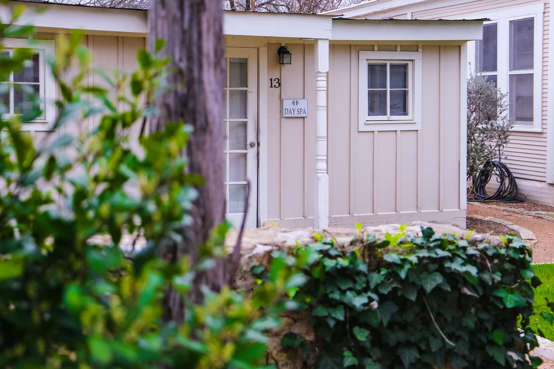 A small house with a porch and a tree in front of it.