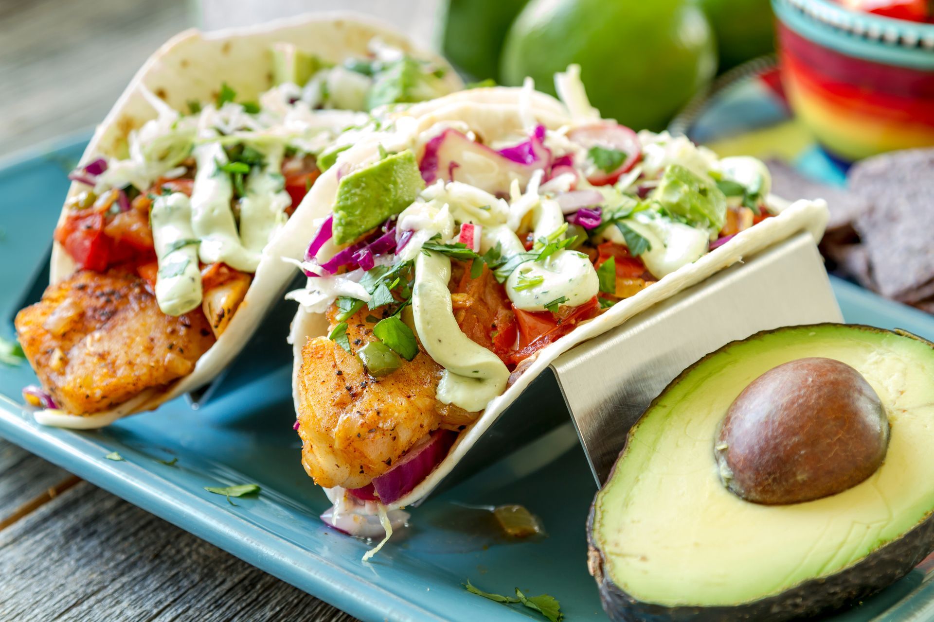 A blue plate topped with fish tacos and an avocado.