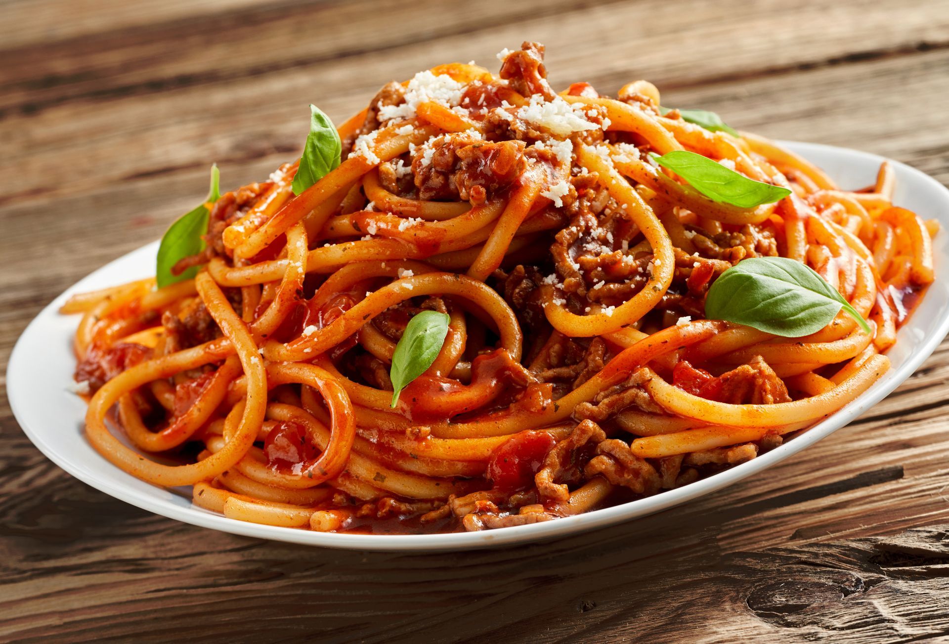 A white plate topped with spaghetti and meat sauce on a wooden table.
