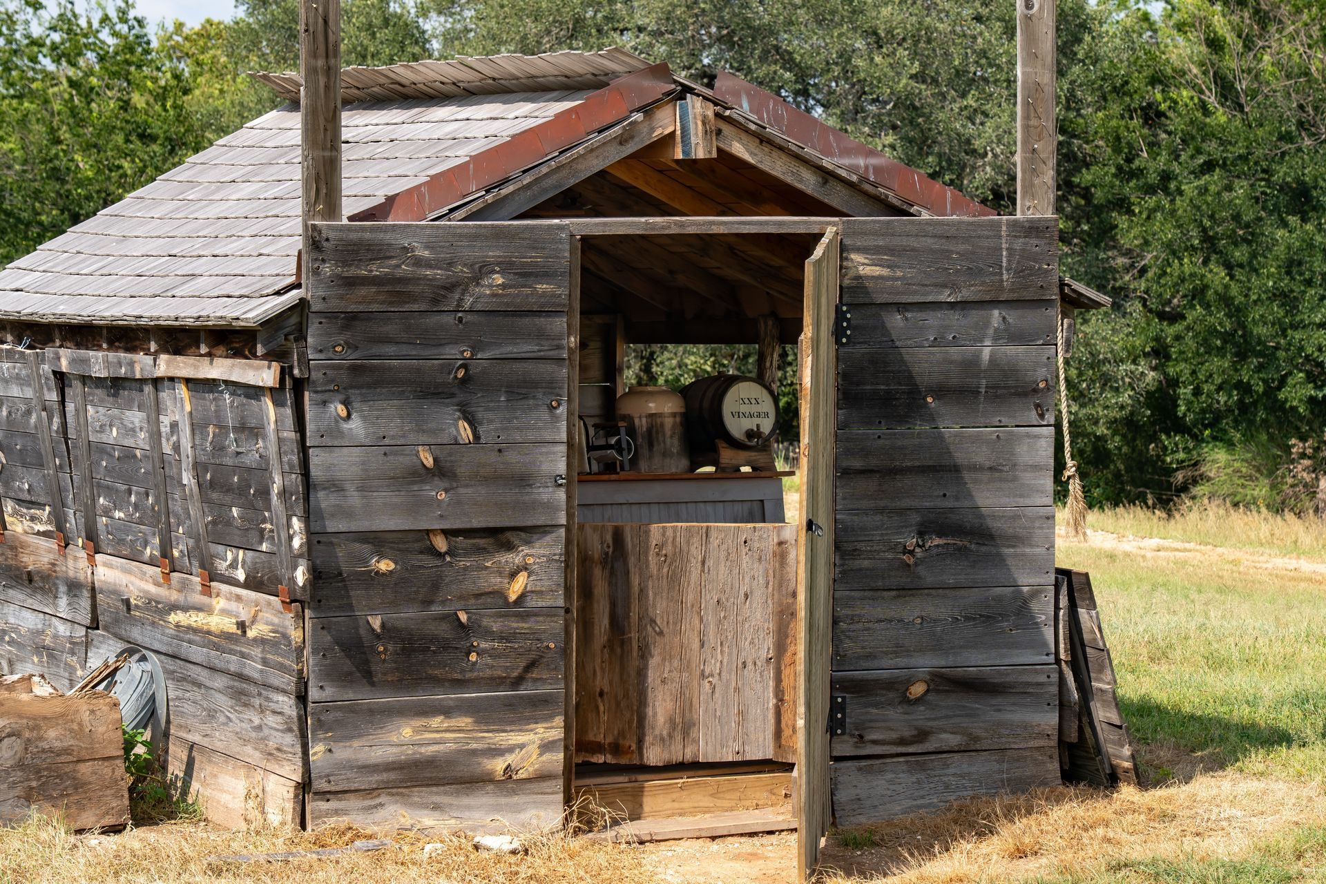 Weathered wooden shed with open door; rusty metal roof.