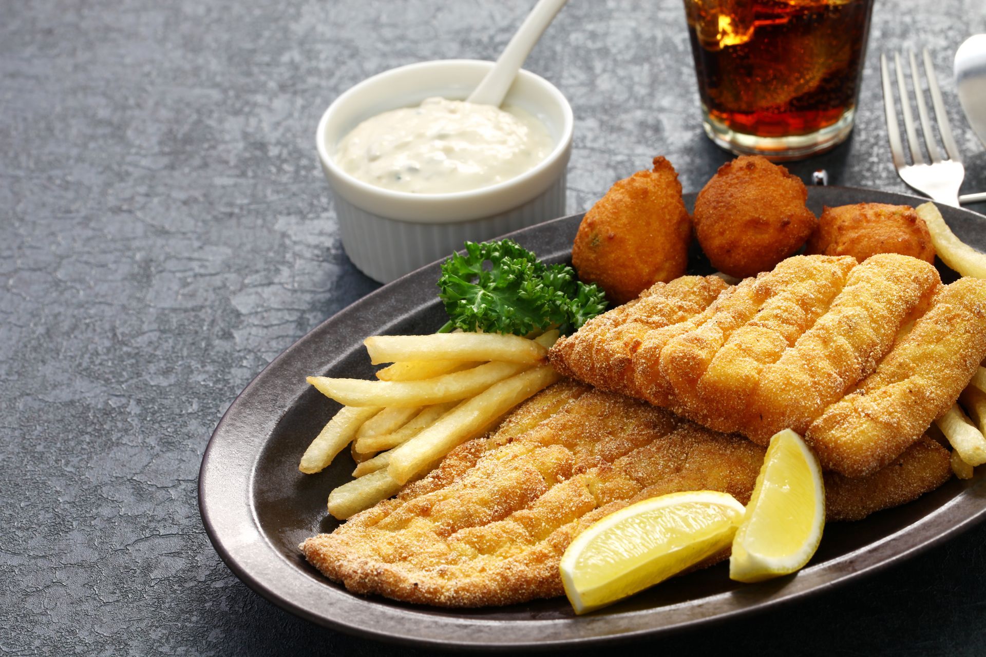 A plate of fried fish with french fries and lemon slices on a table.