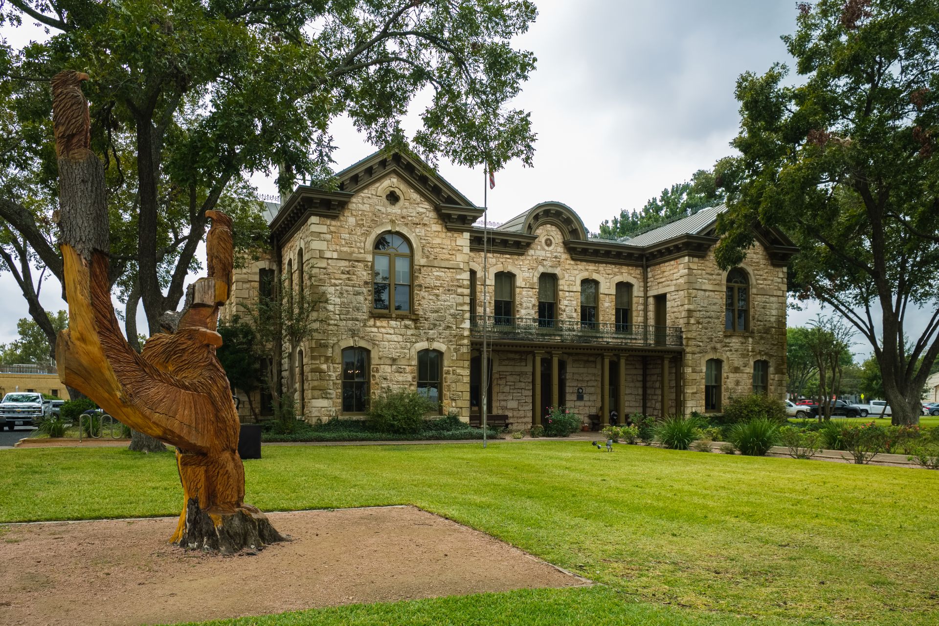 A large stone building with a statue of a dinosaur in front of it.
