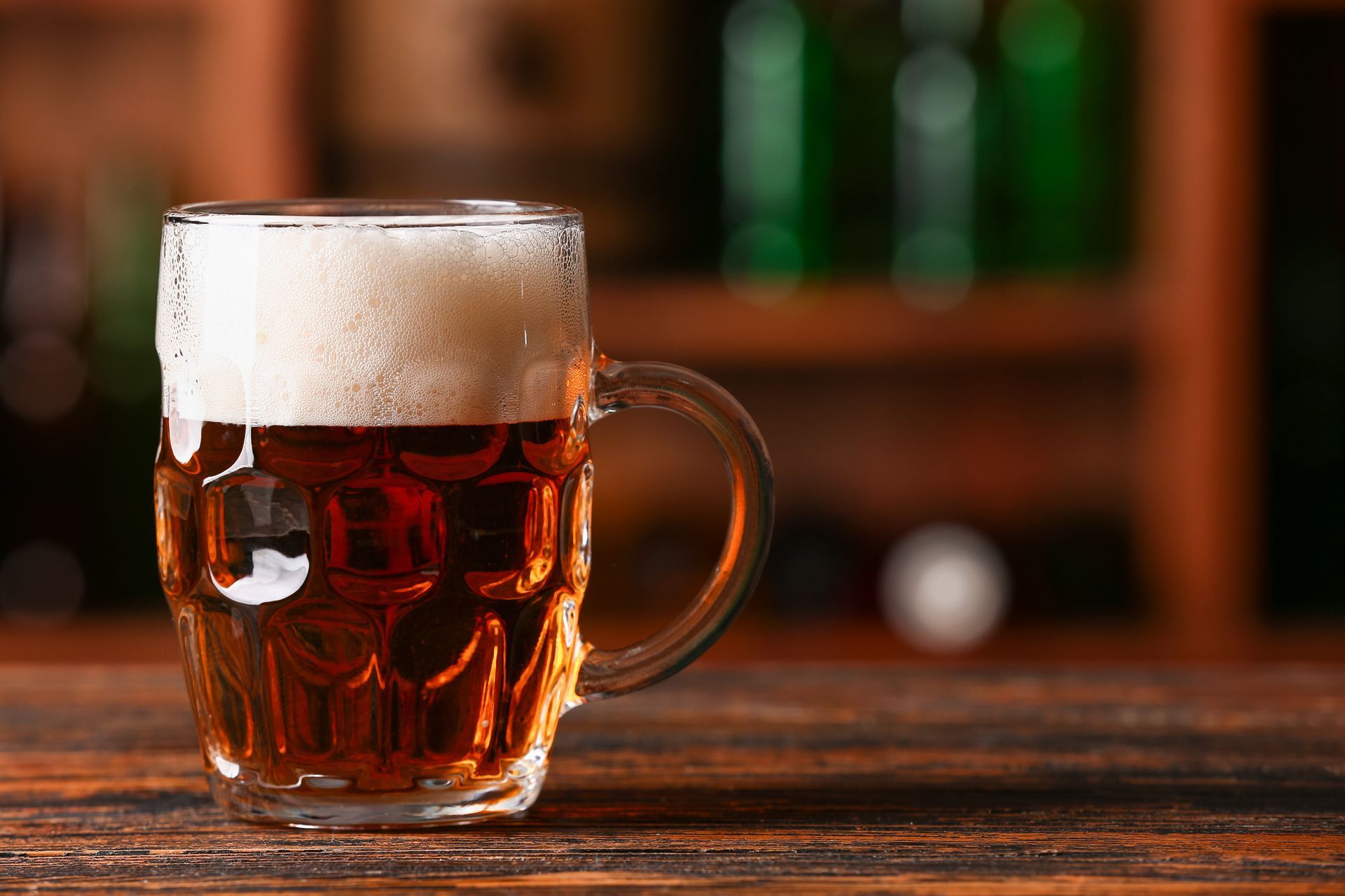 A glass of beer is sitting on a wooden table.