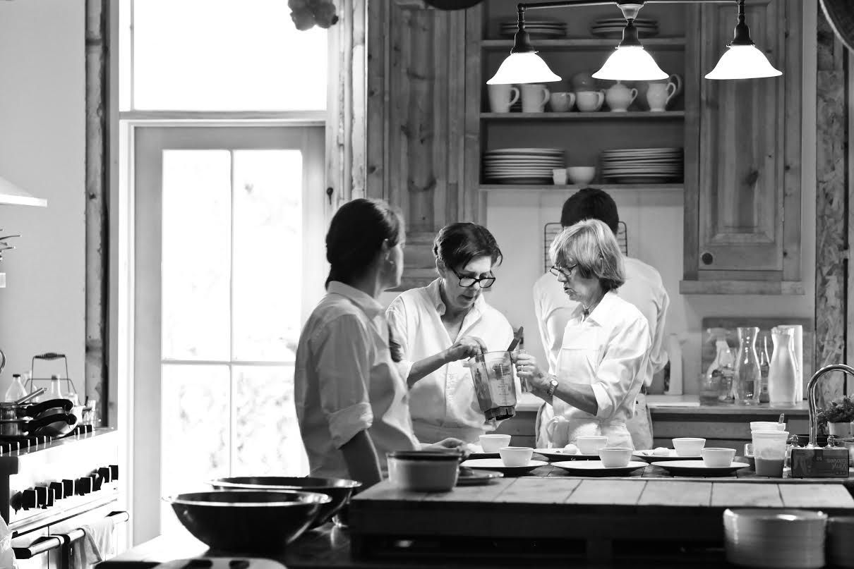 A group of people are standing in a kitchen preparing food.