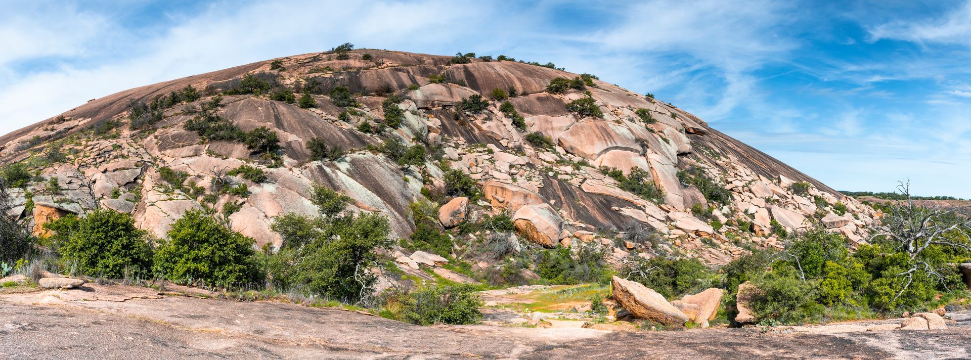 A large rocky hill with trees on it and a blue sky in the background.
