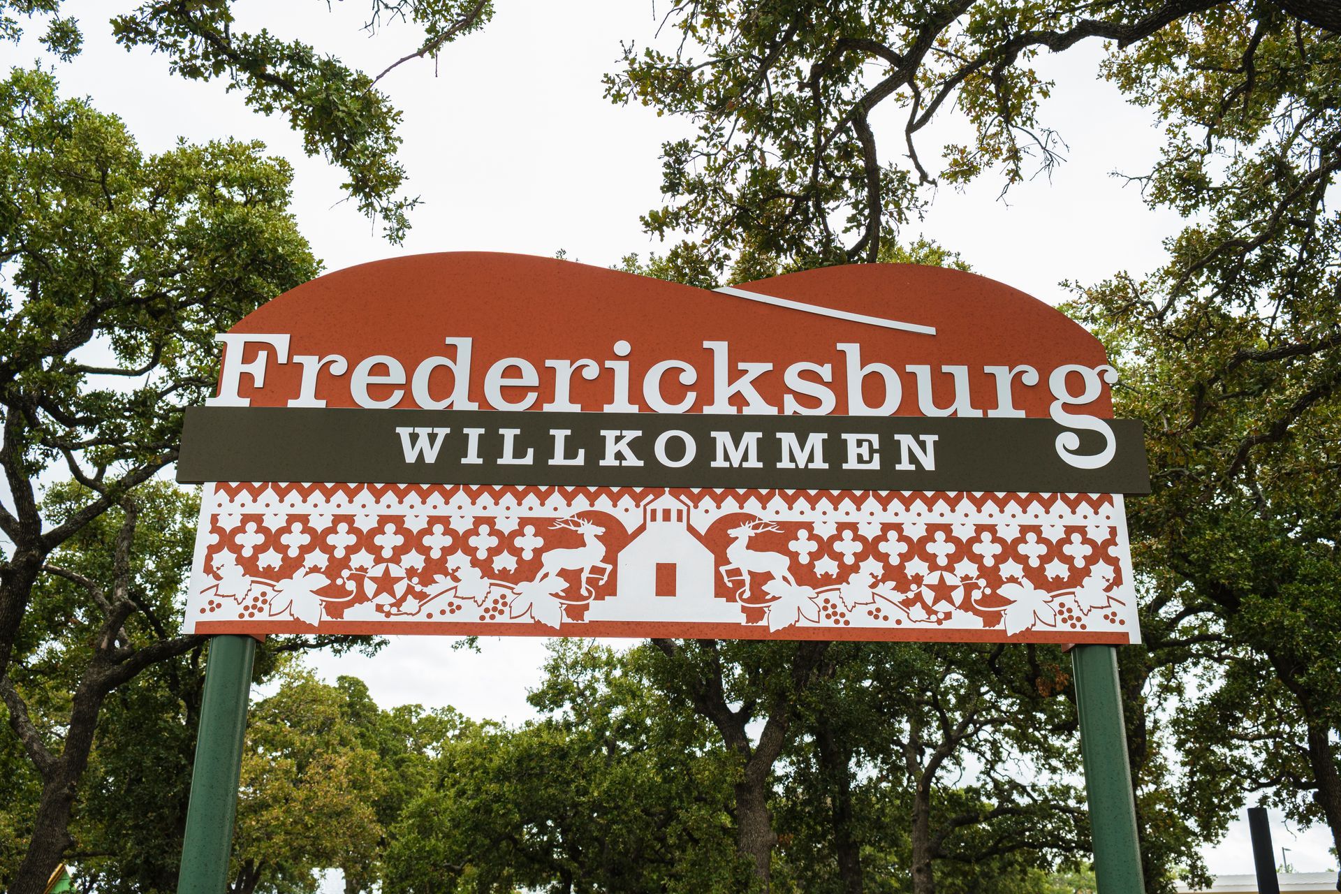 A sign for fredericksburg willkommen is surrounded by trees