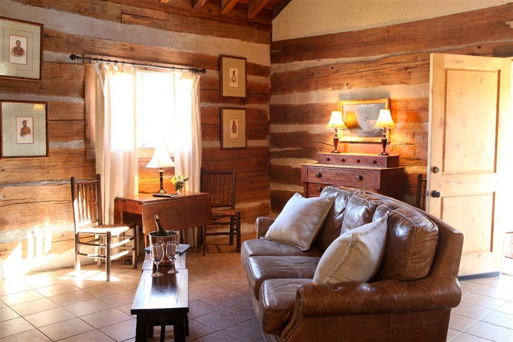 A living room in a log cabin with a couch and chairs