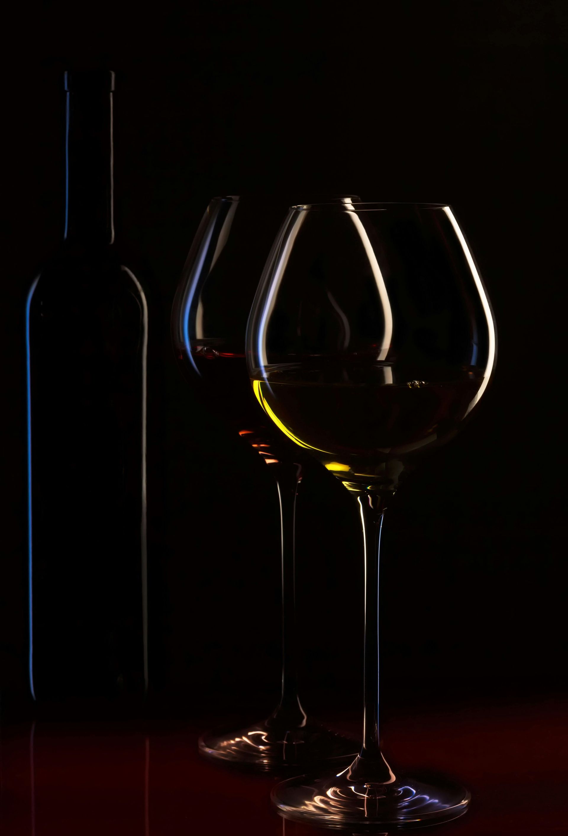 Two wine glasses and a bottle of wine on a table.