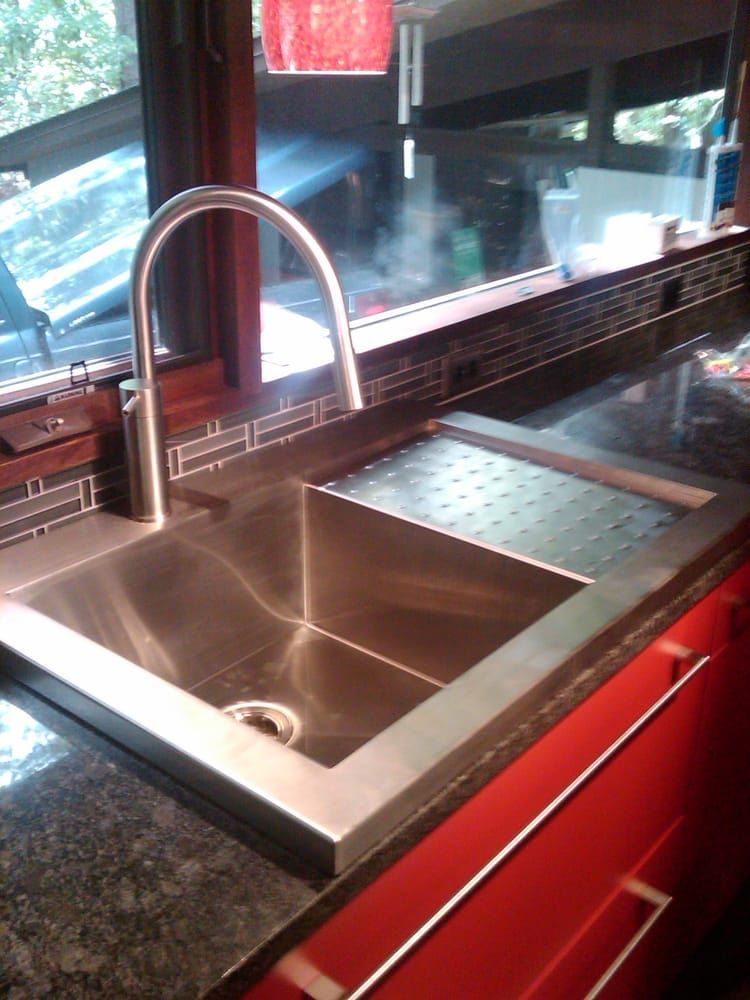 a stainless steel sink in a kitchen with red cabinets