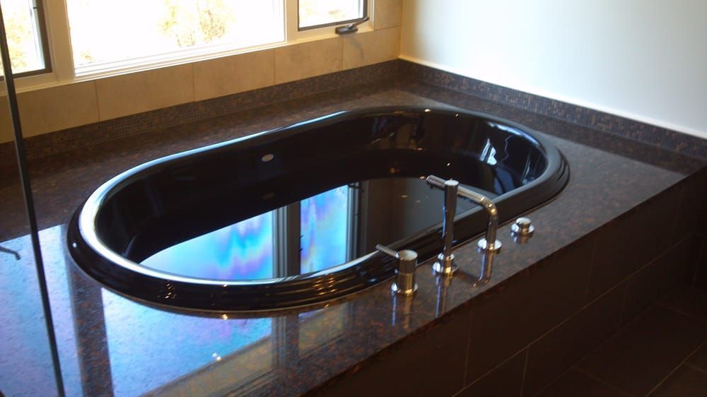 a black bathtub sits in a bathroom next to a window