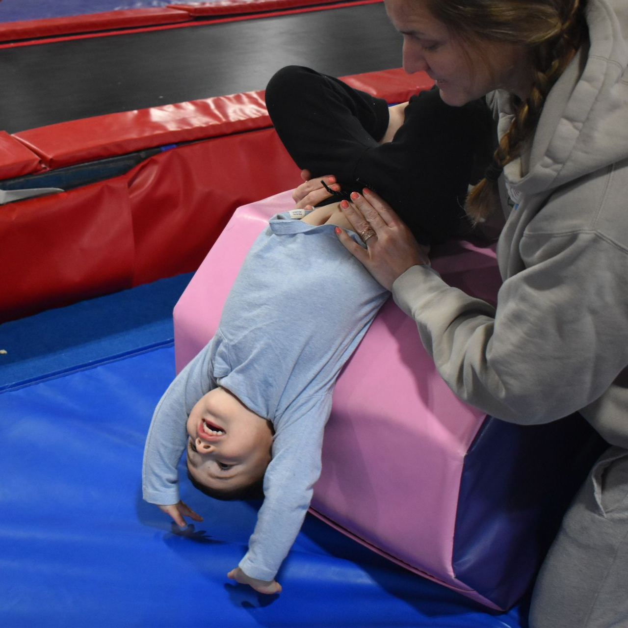A young boy is doing a handstand on a mat