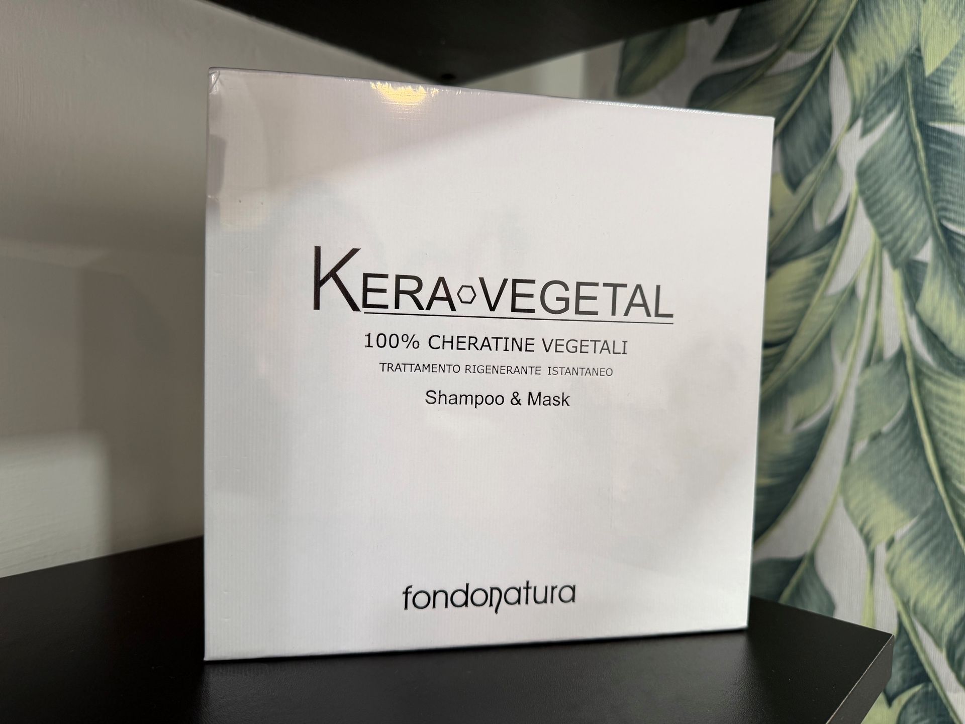 Scatola bianca di shampoo e maschera Kera Vegetal su una superficie nera.