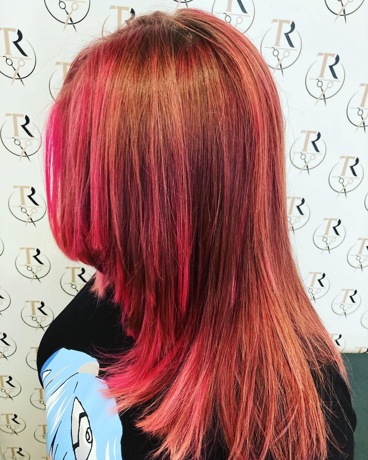 Donna con lunghi capelli rossi scalati, più scuri alle radici e con riflessi rosa.