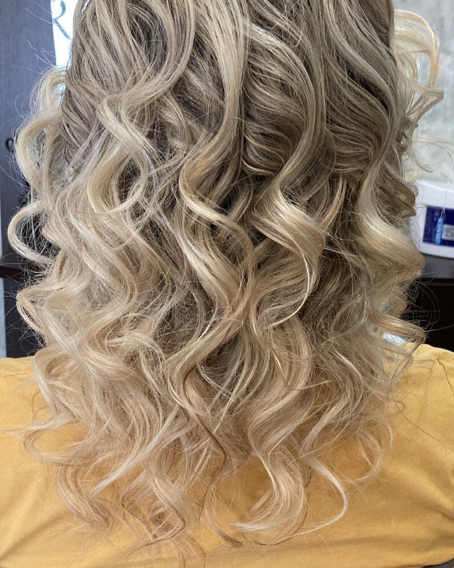 Capelli biondi ondulati e acconciati in riccioli, su una maglietta gialla, in un salone di bellezza.