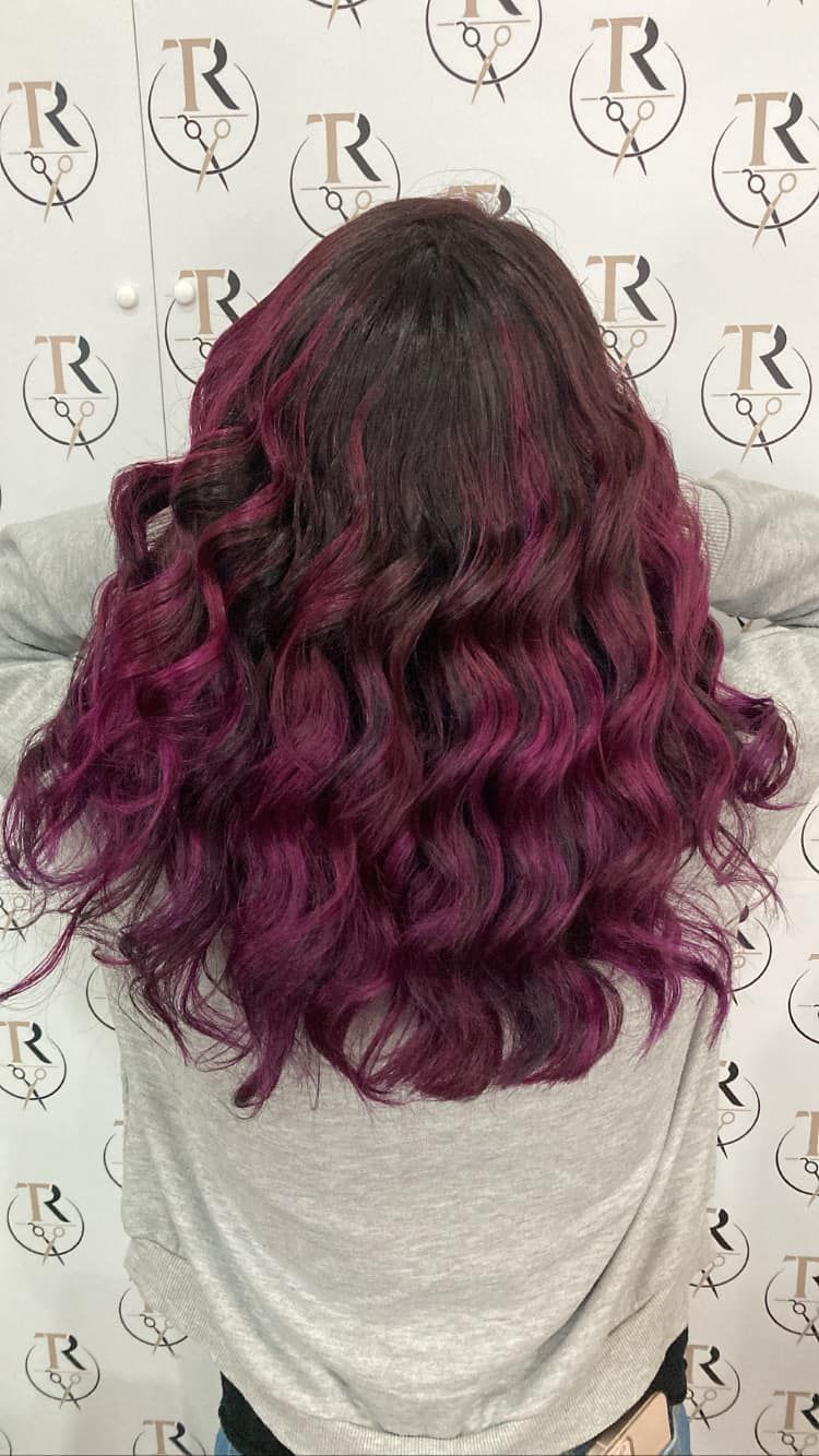 Donna con capelli castano scuro che sfumano in vivaci riccioli color magenta.